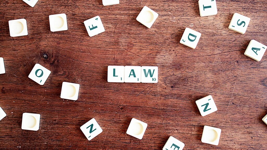 Scrabble tiles spelling 'LAW' on a wooden table, symbolizing connections to education and legality.