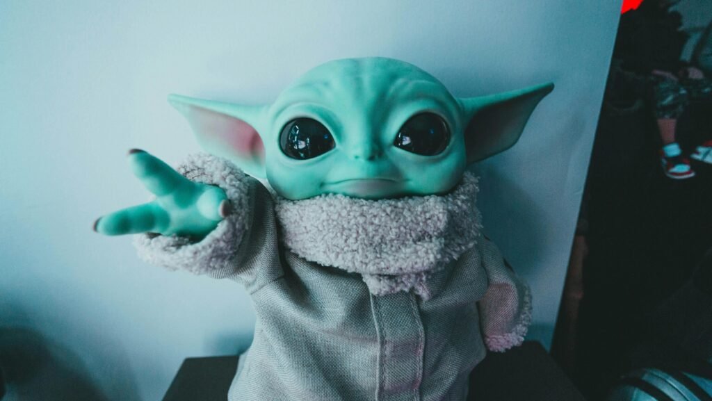 Cute Baby Yoda toy figurine in a cozy outfit reaching forward, perfect for fans.