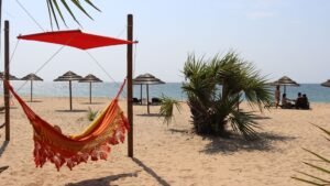 Serene beach scene with a hammock under palm trees in Caboledo, Angola, ideal for a tropical escape.